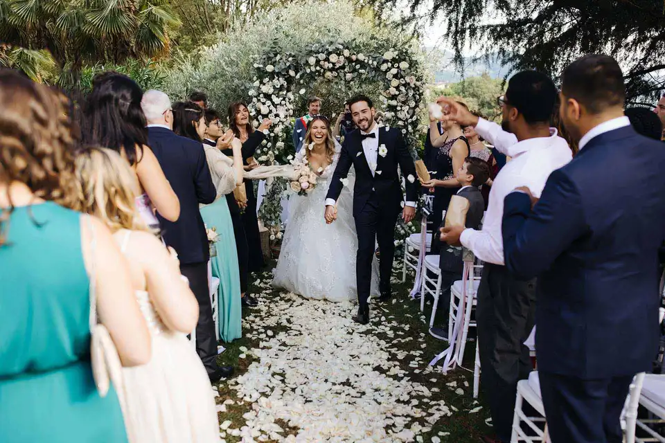 A couple leaving their wedding ceremony at Castello di Rossino in Italy, guests on either side.